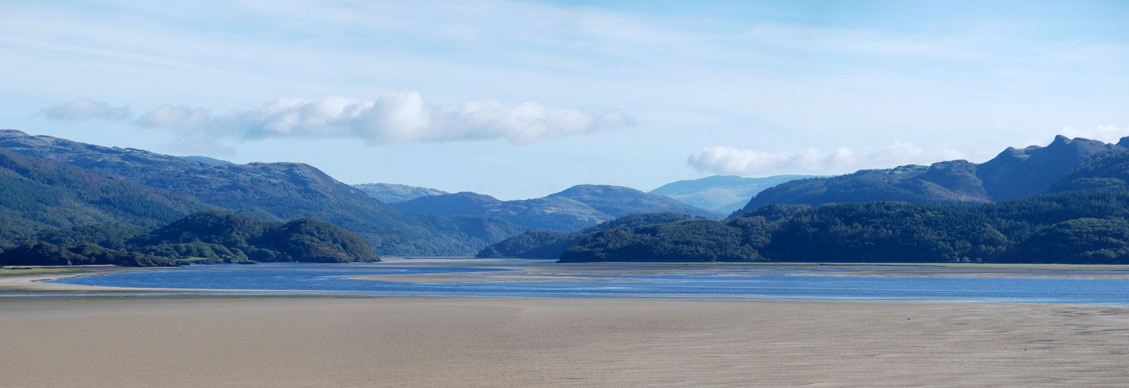 a sandy beach sits between many large hills