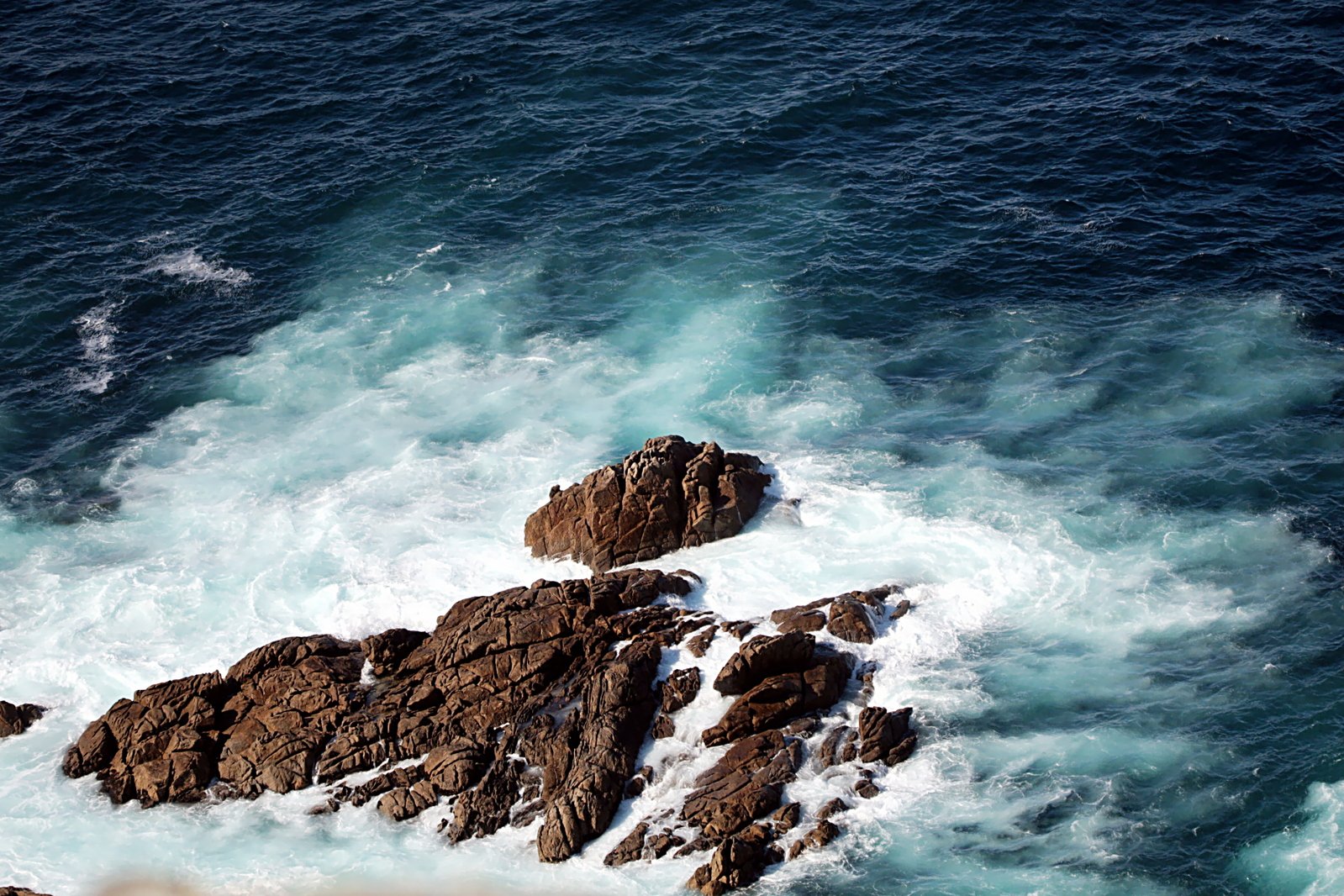 rough waters breaking up along the rocks at a coastline