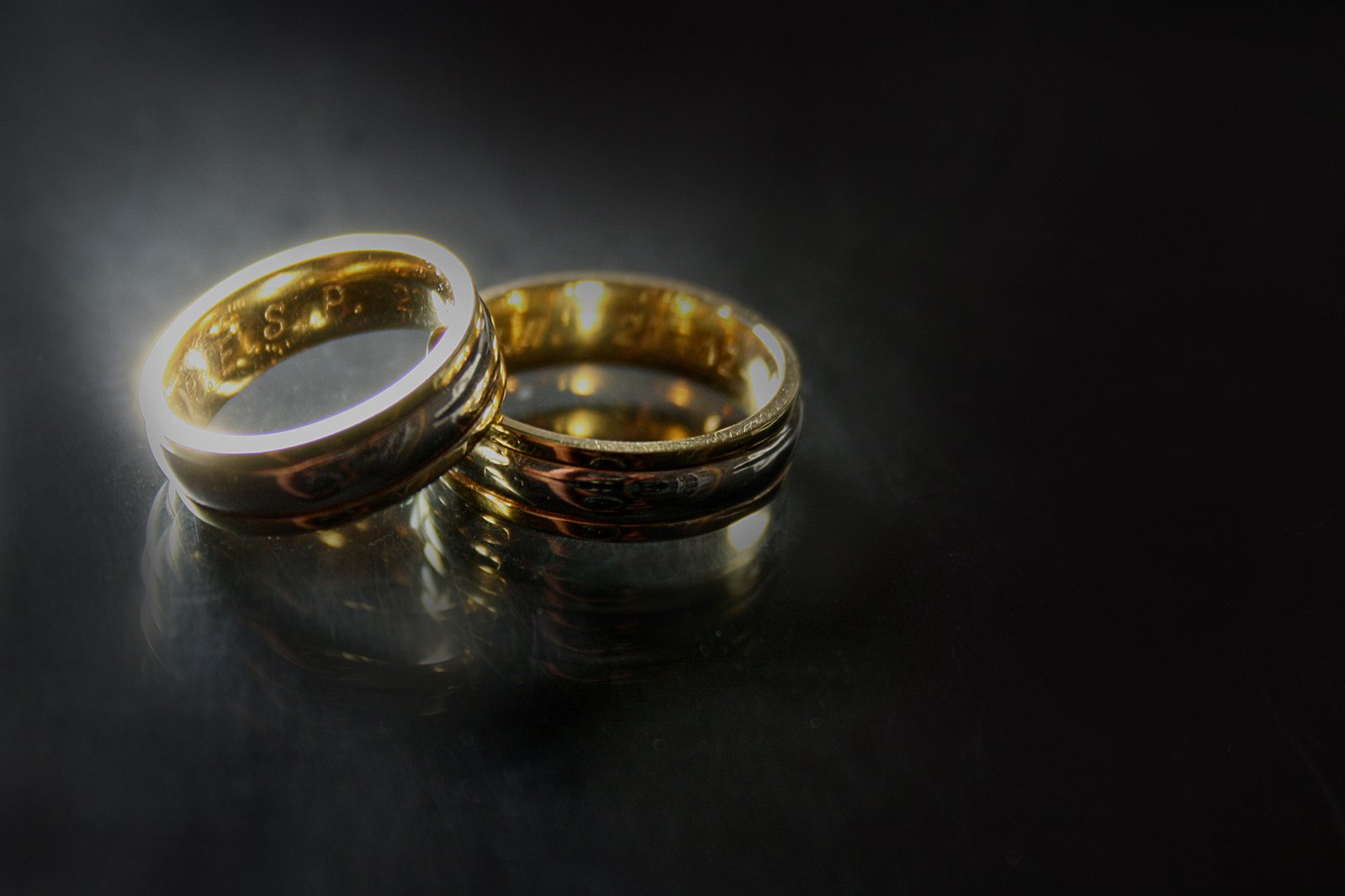 two golden wedding rings on a reflective surface