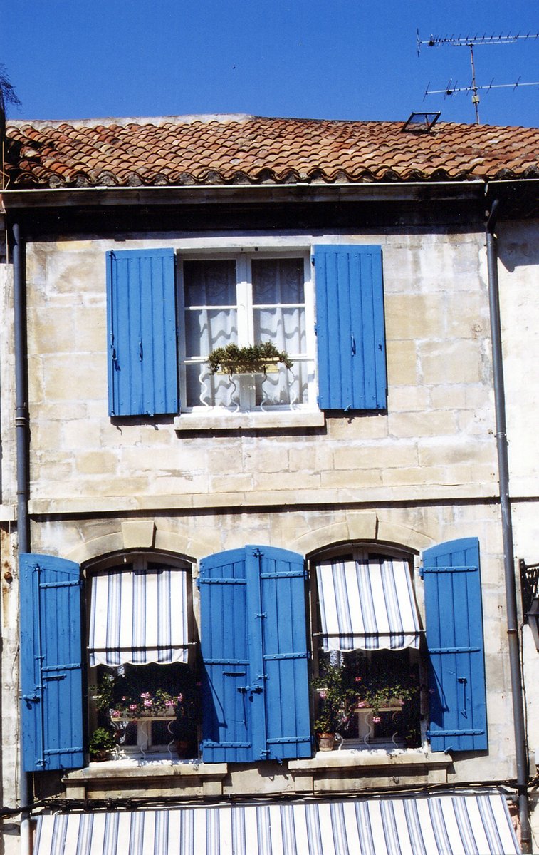 a store that has blue shutters and white striped awning