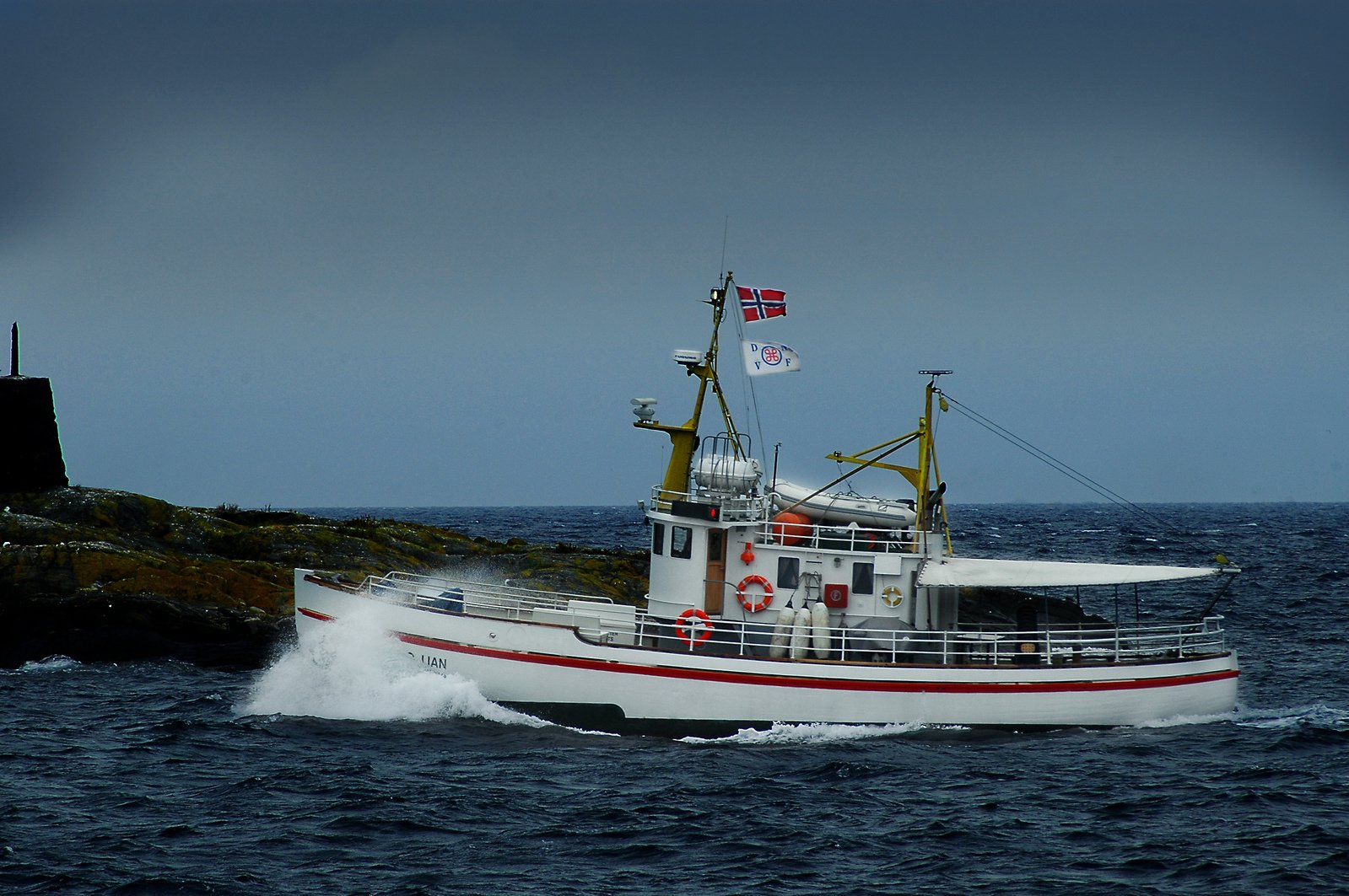 a boat traveling through the ocean by a lighthouse