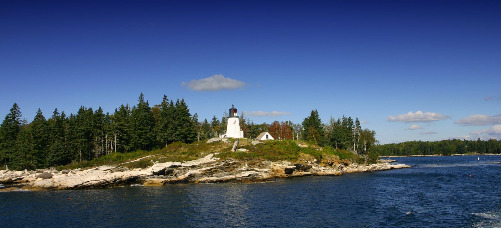 a small island with a lighthouse sits in the middle of a lake