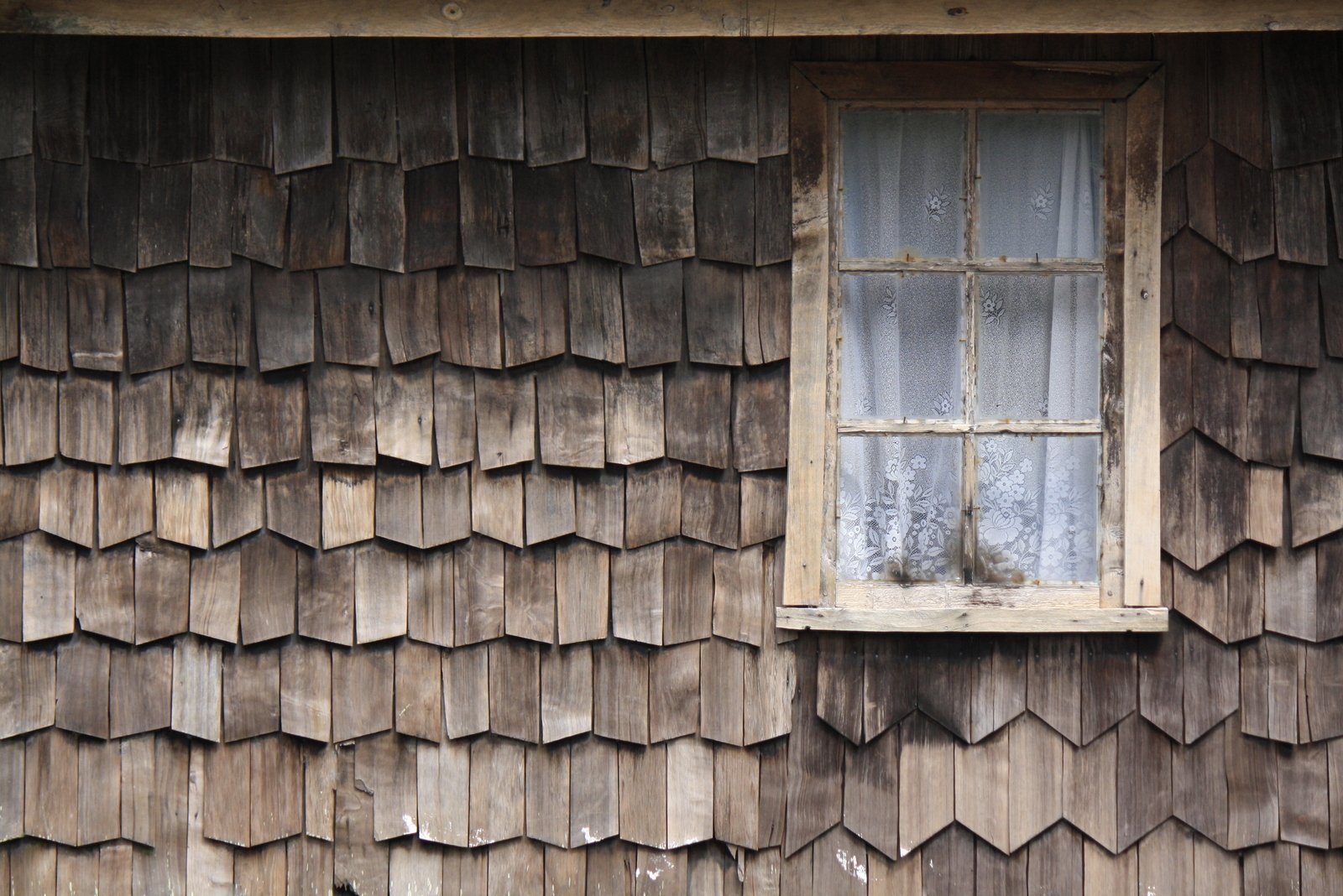 a window on the side of an old, wooden building