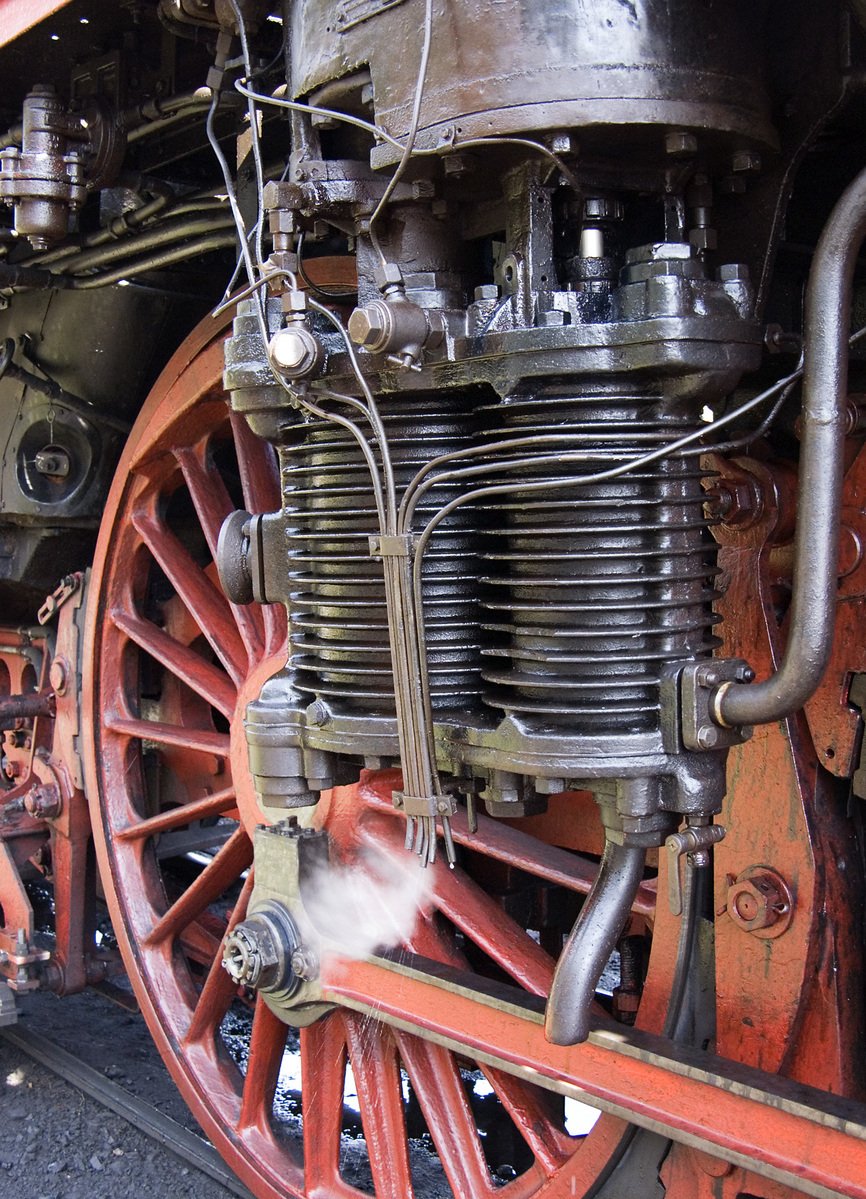 an antique steam engine that has a white steam coming out of it