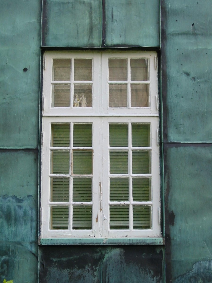 a white window on the outside wall of an old building