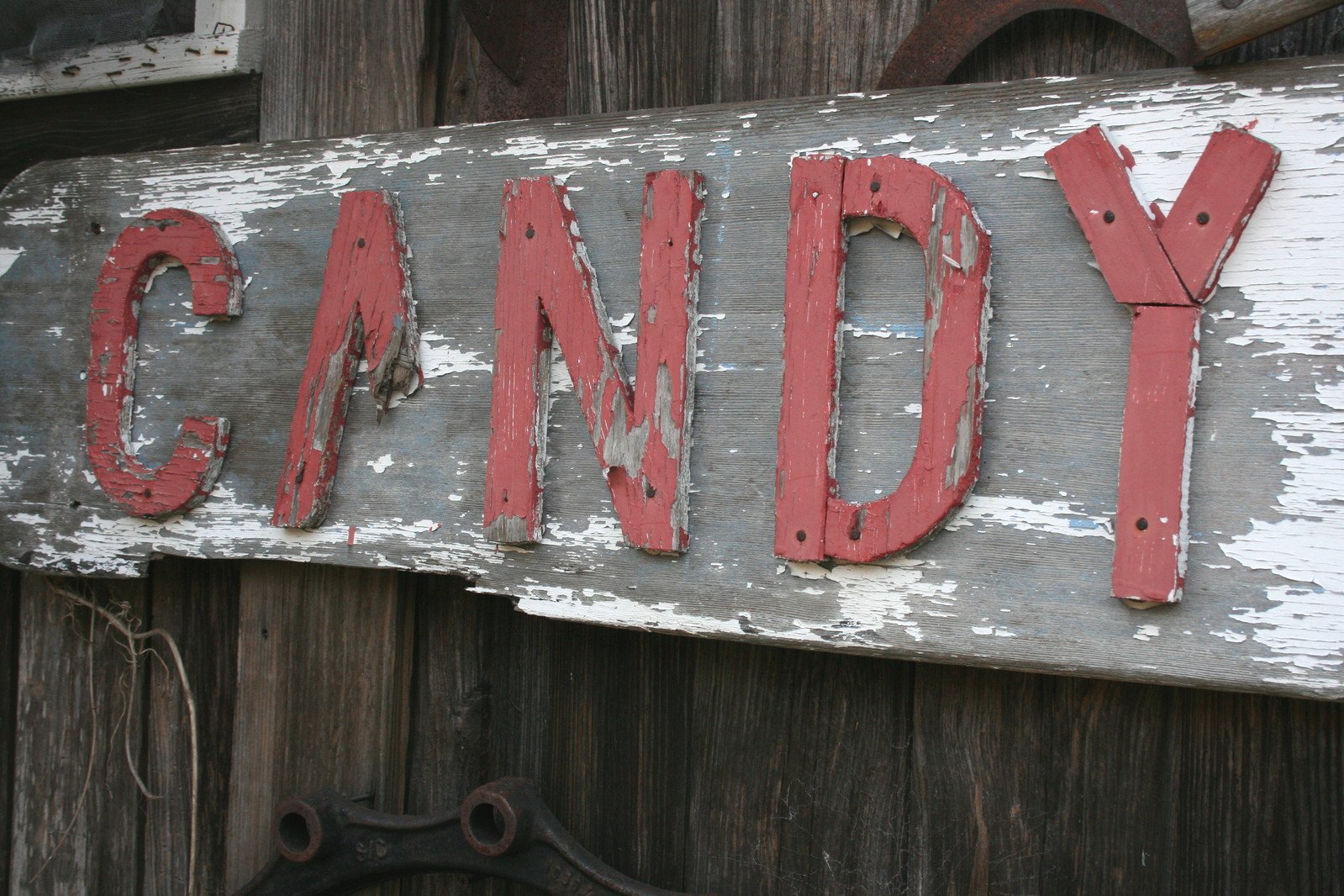 an old sign advertising candy and hanging on the side of a building