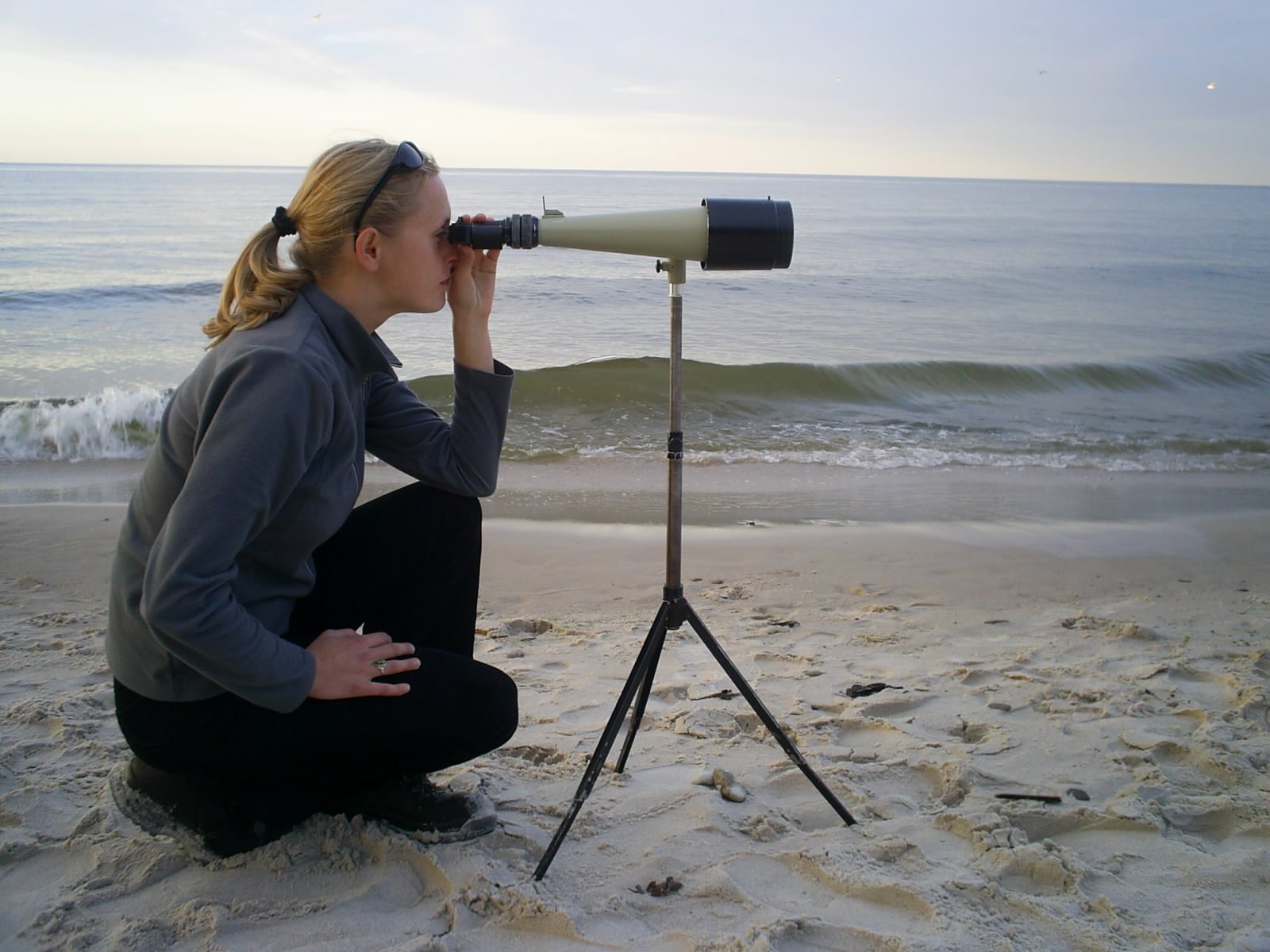 a girl looking through a telescope at the ocean