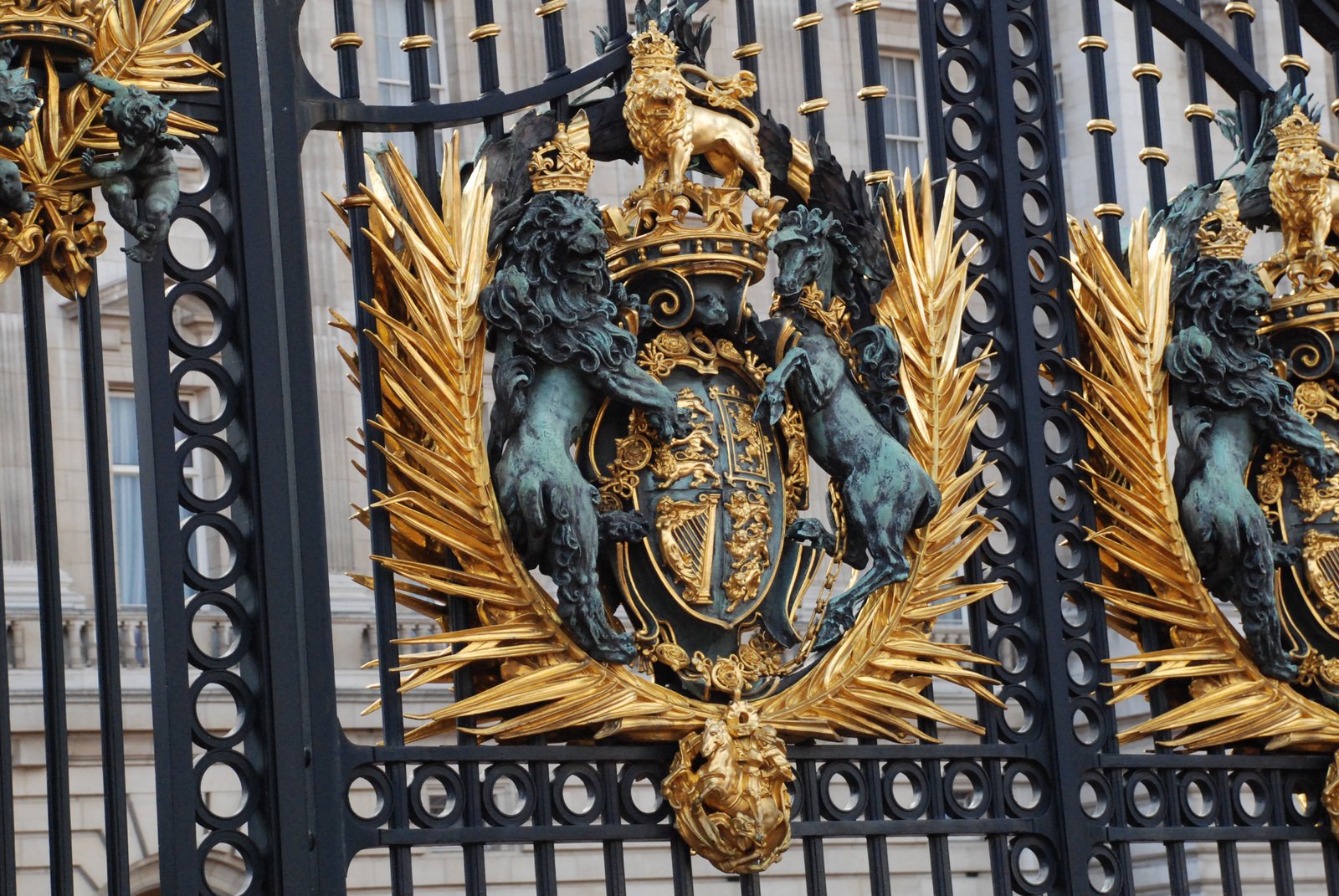 three gold coat of arms hang on the side of the gates