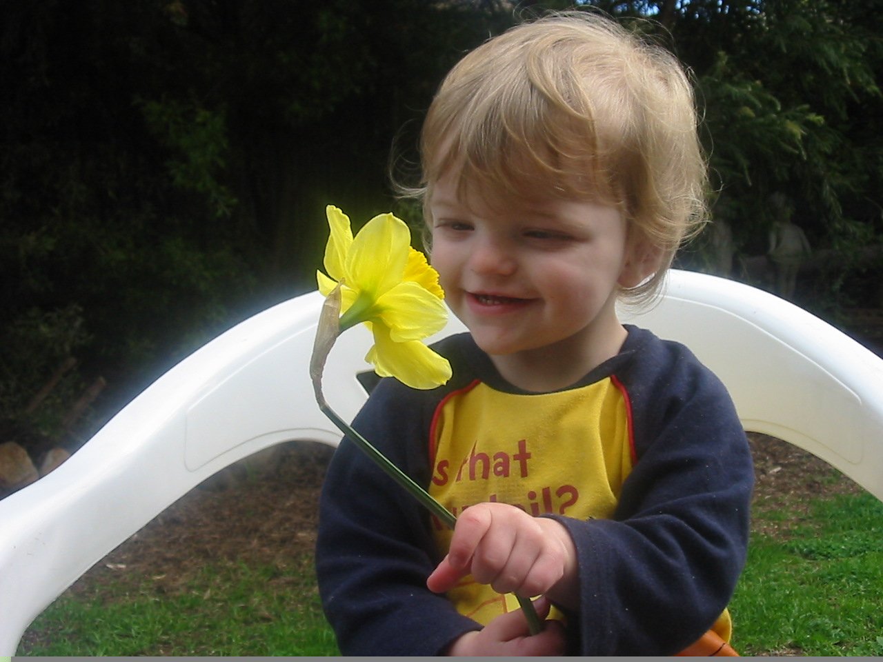 the child is smiling with the yellow flower