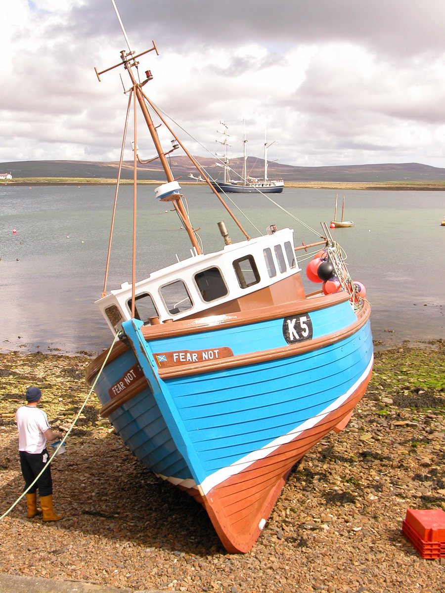 an old boat with ropes tied on the shore