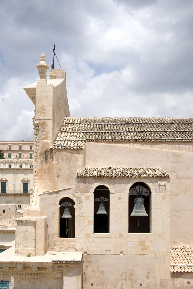 a stone building with three bells on top of it