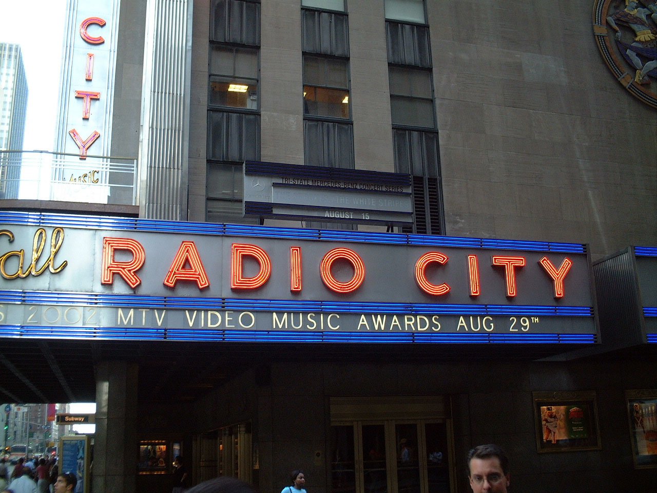 the radio city sign is bright neon in front of the entrance