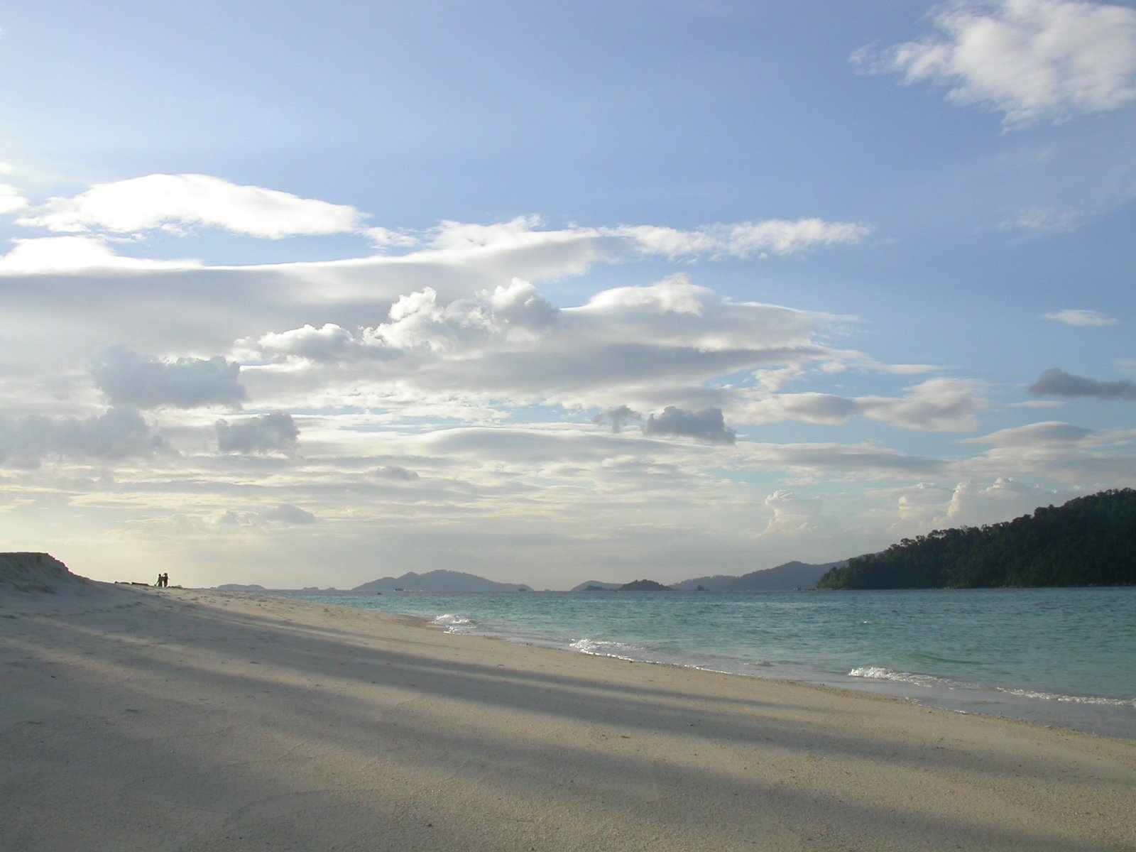 the beach with people in it is next to the water