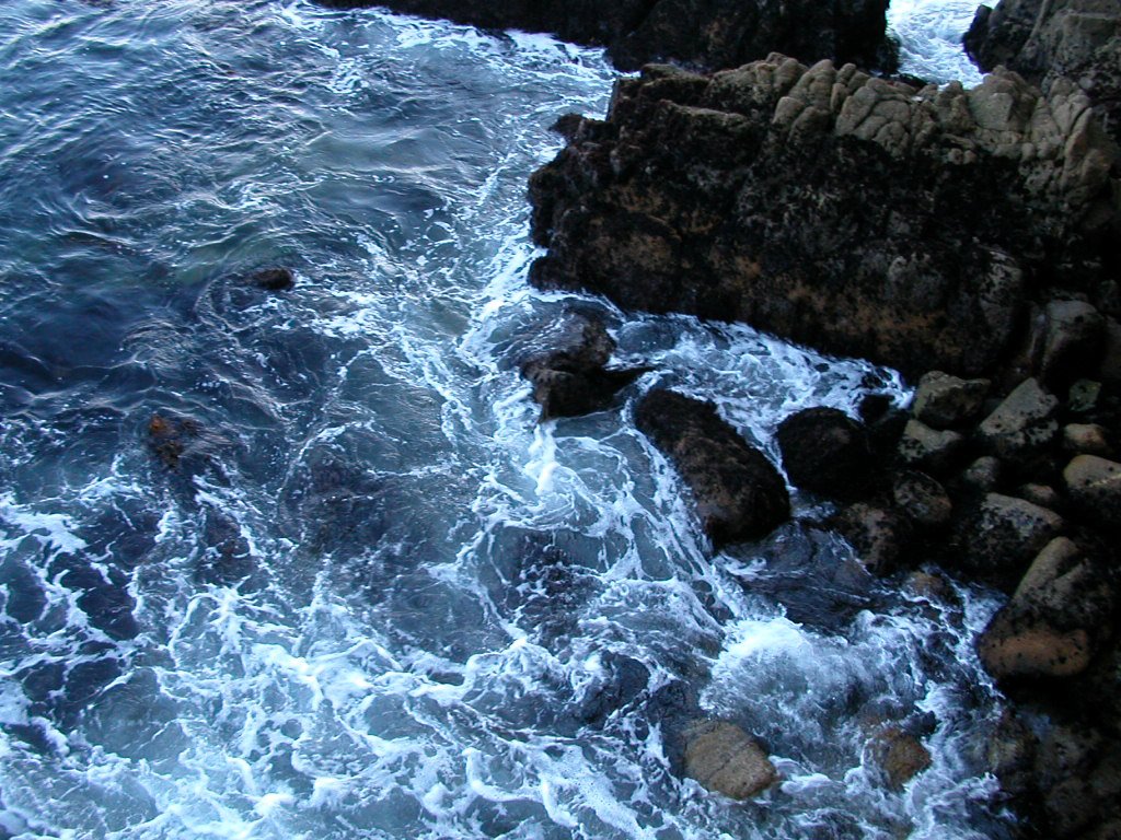 ocean water breaking and crashing next to large rock formations