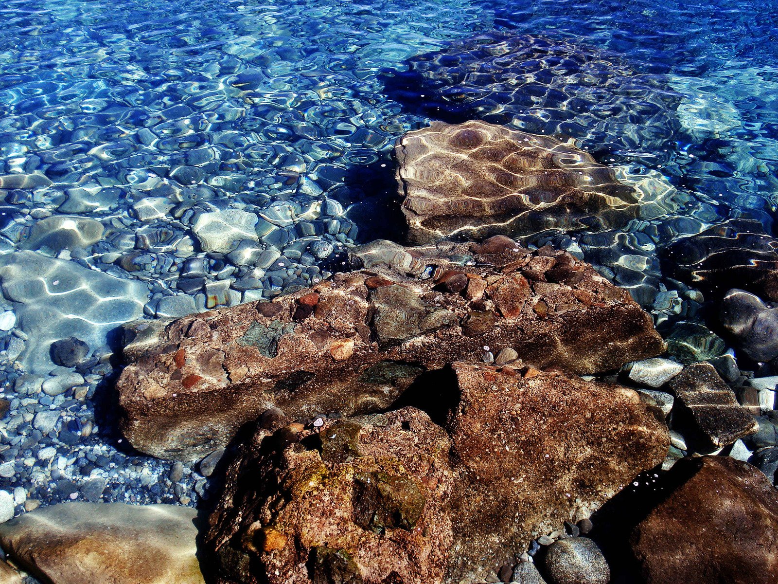 rocks and clear blue water with rocks and water underneath them