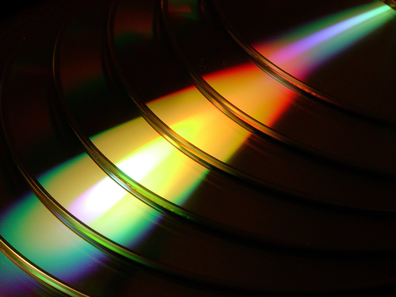 a rainbow light shows through several cd's