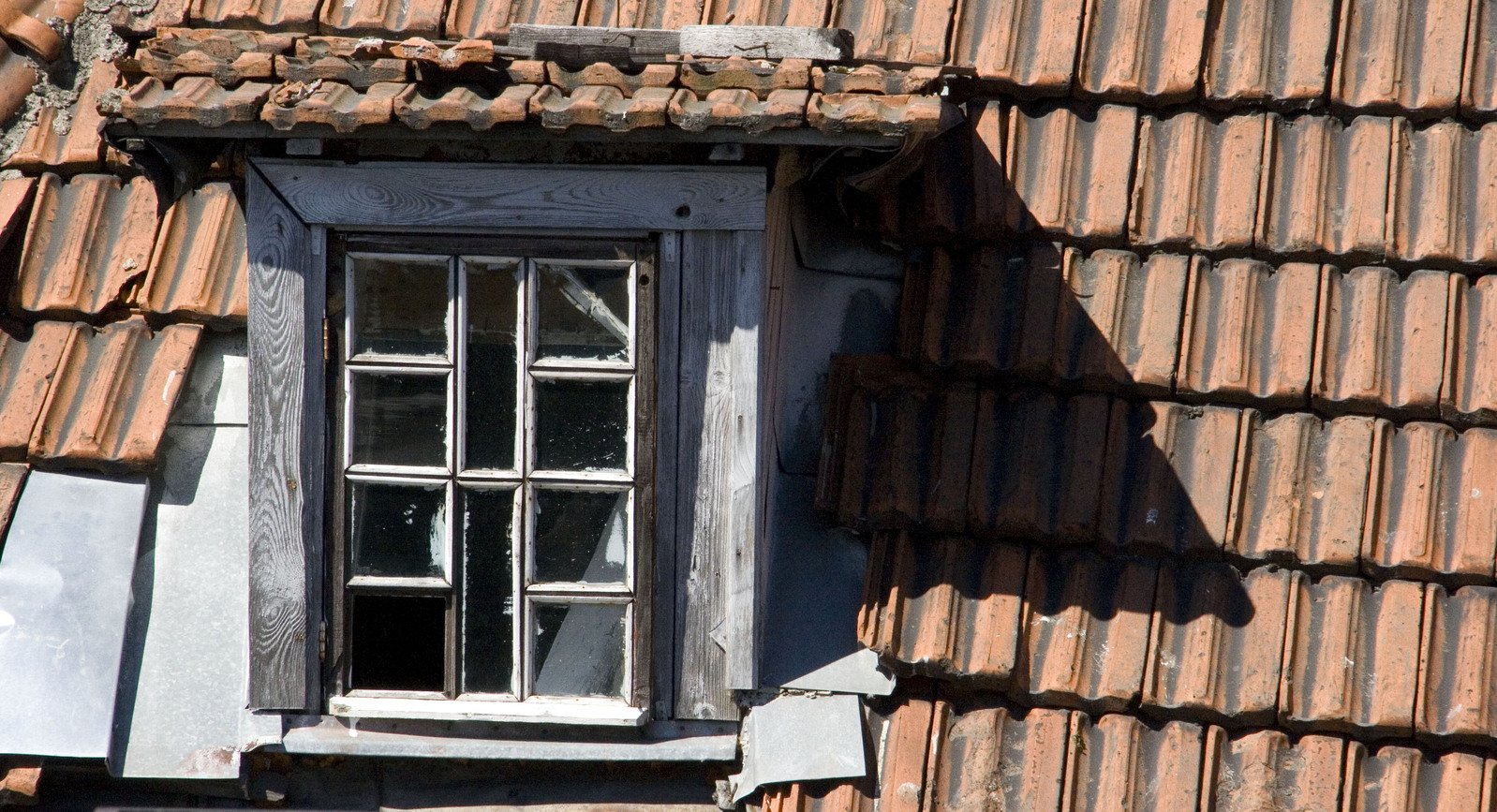 a window on a bricked house with tile roof and red tiles