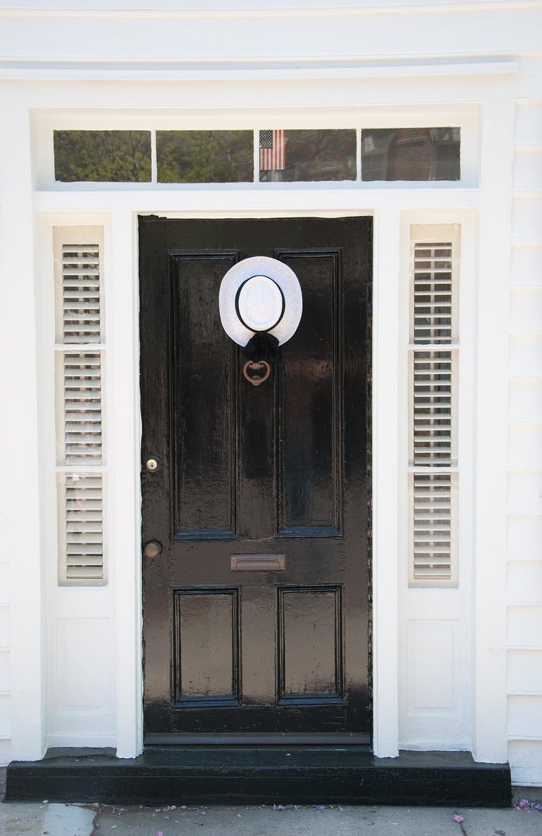 a black door with a white and blue hat above the top half of the door