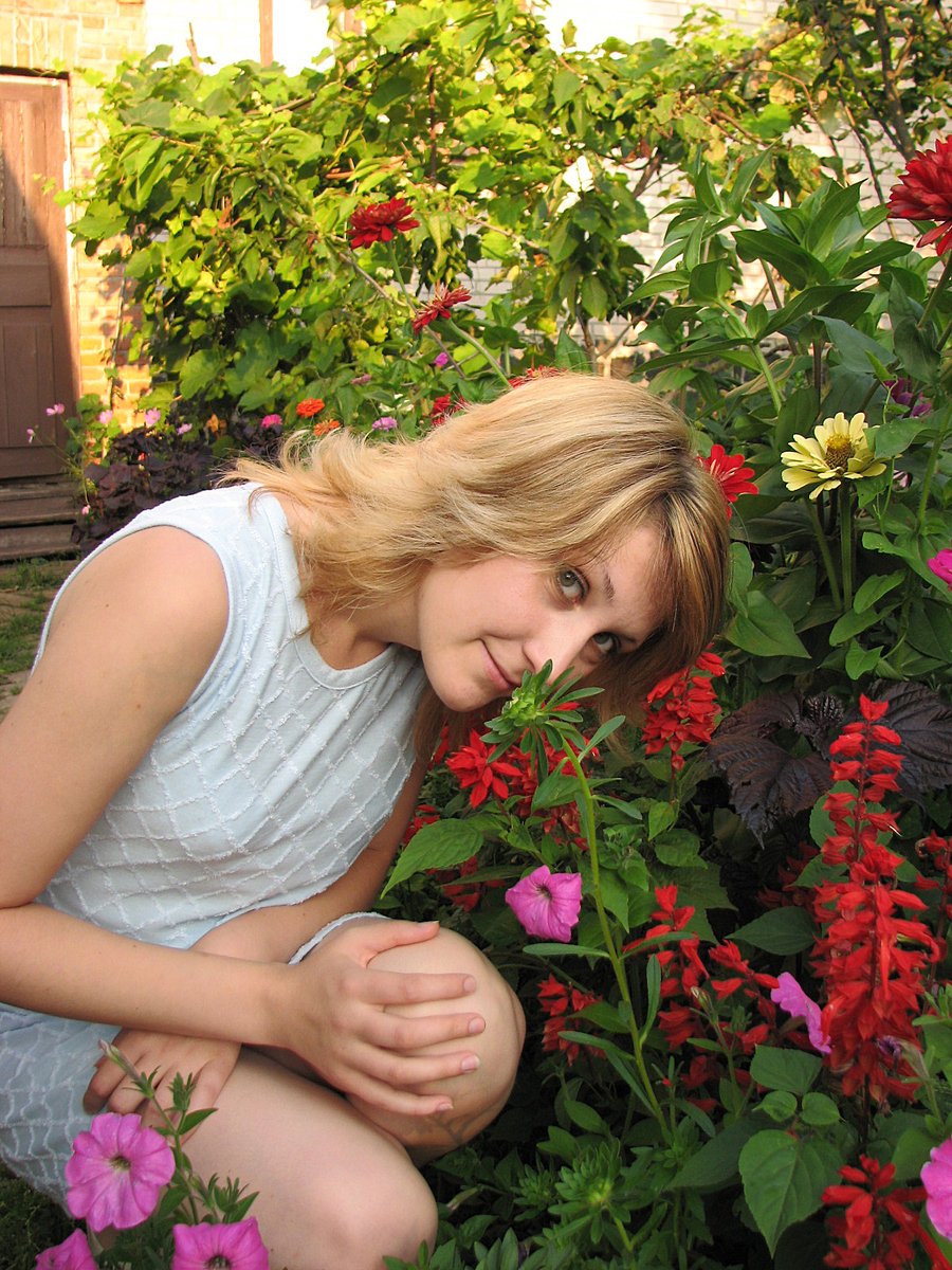 a  sitting in flowers looking at the camera