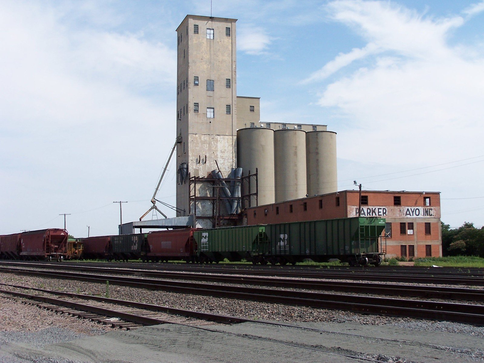 two industrial buildings, one on the right and one on the left, are behind railroad tracks
