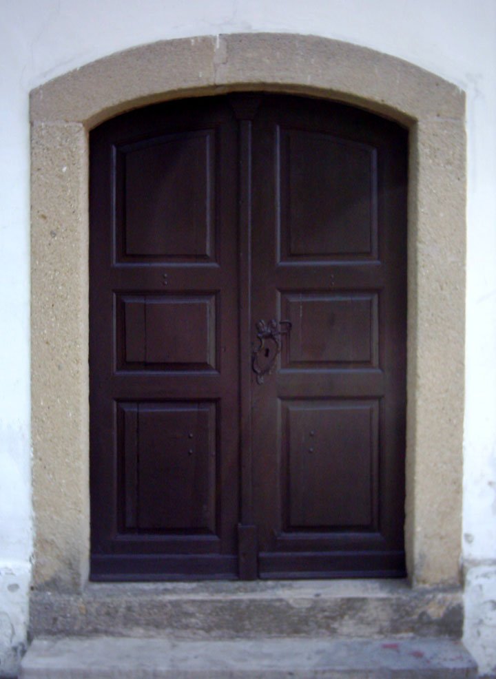 an empty bench sitting in front of a door