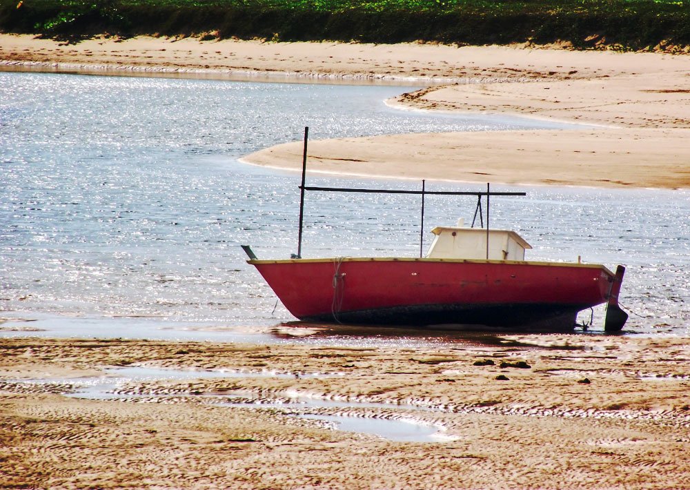 a red boat sitting on top of a beach