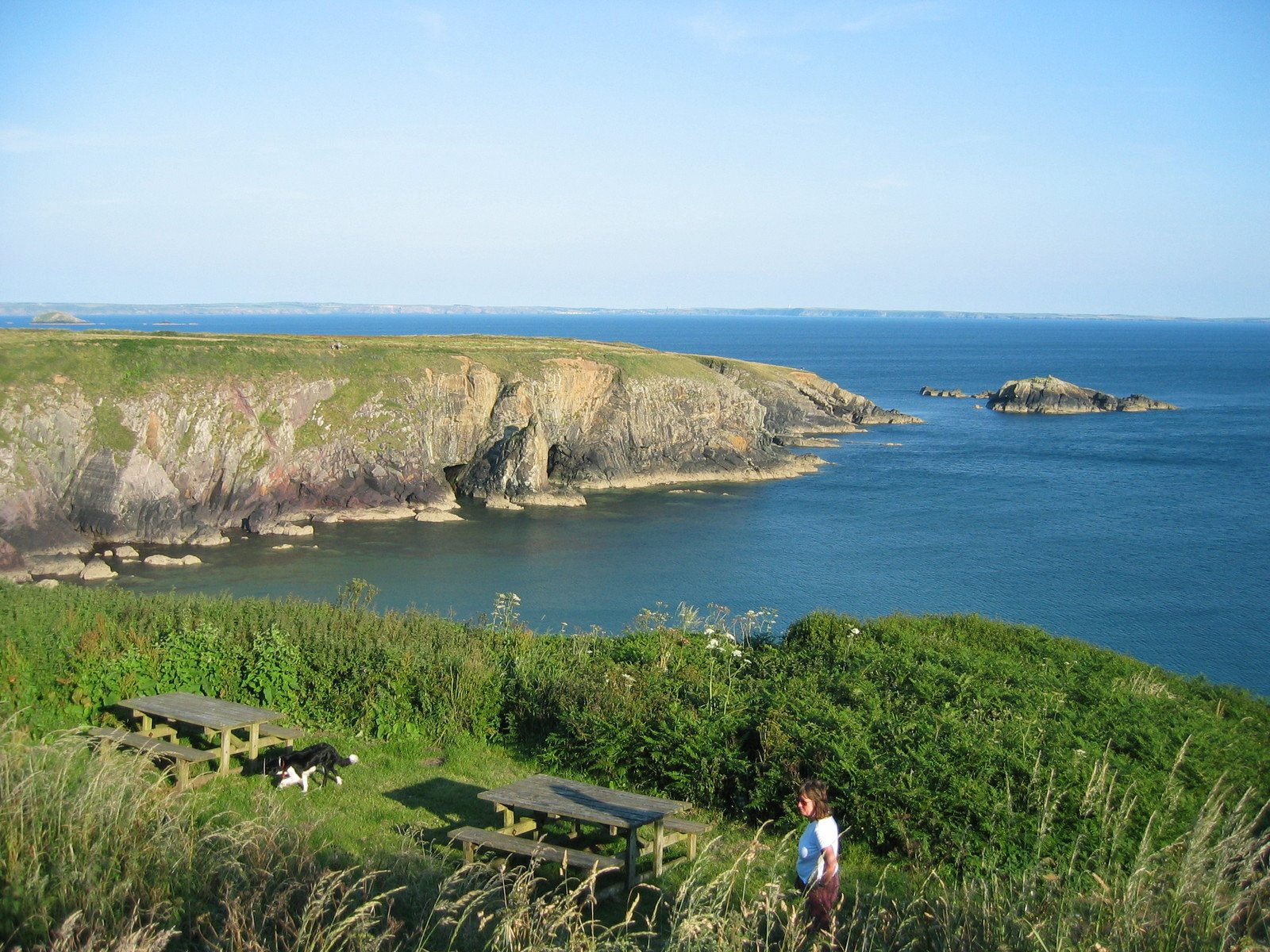 a woman is on a grassy hill by some water