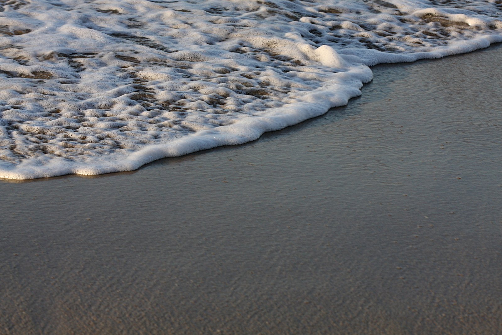 the foamy waves are on the sandy beach