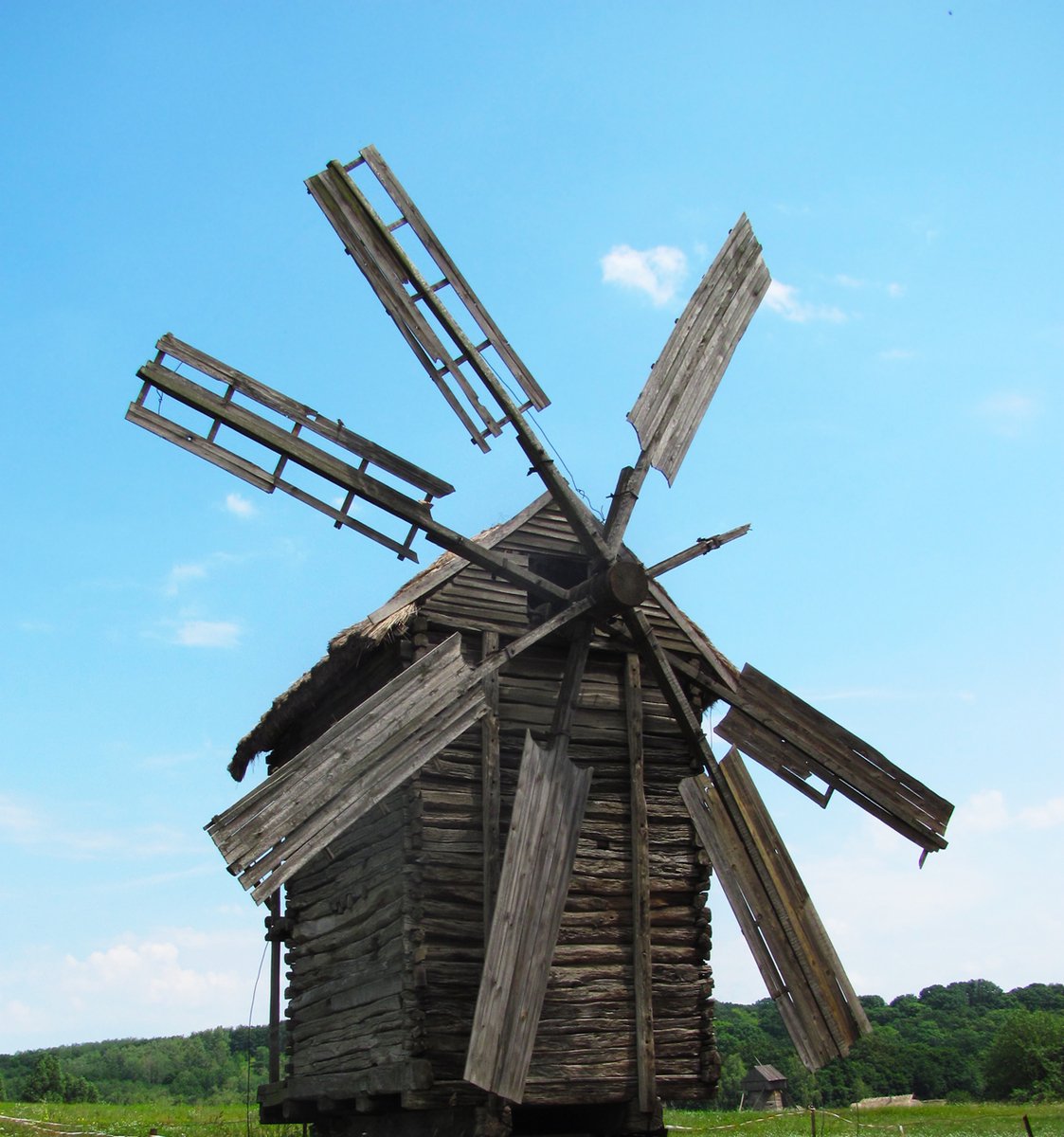 a old dilapidated wood building with four broken windmill blades