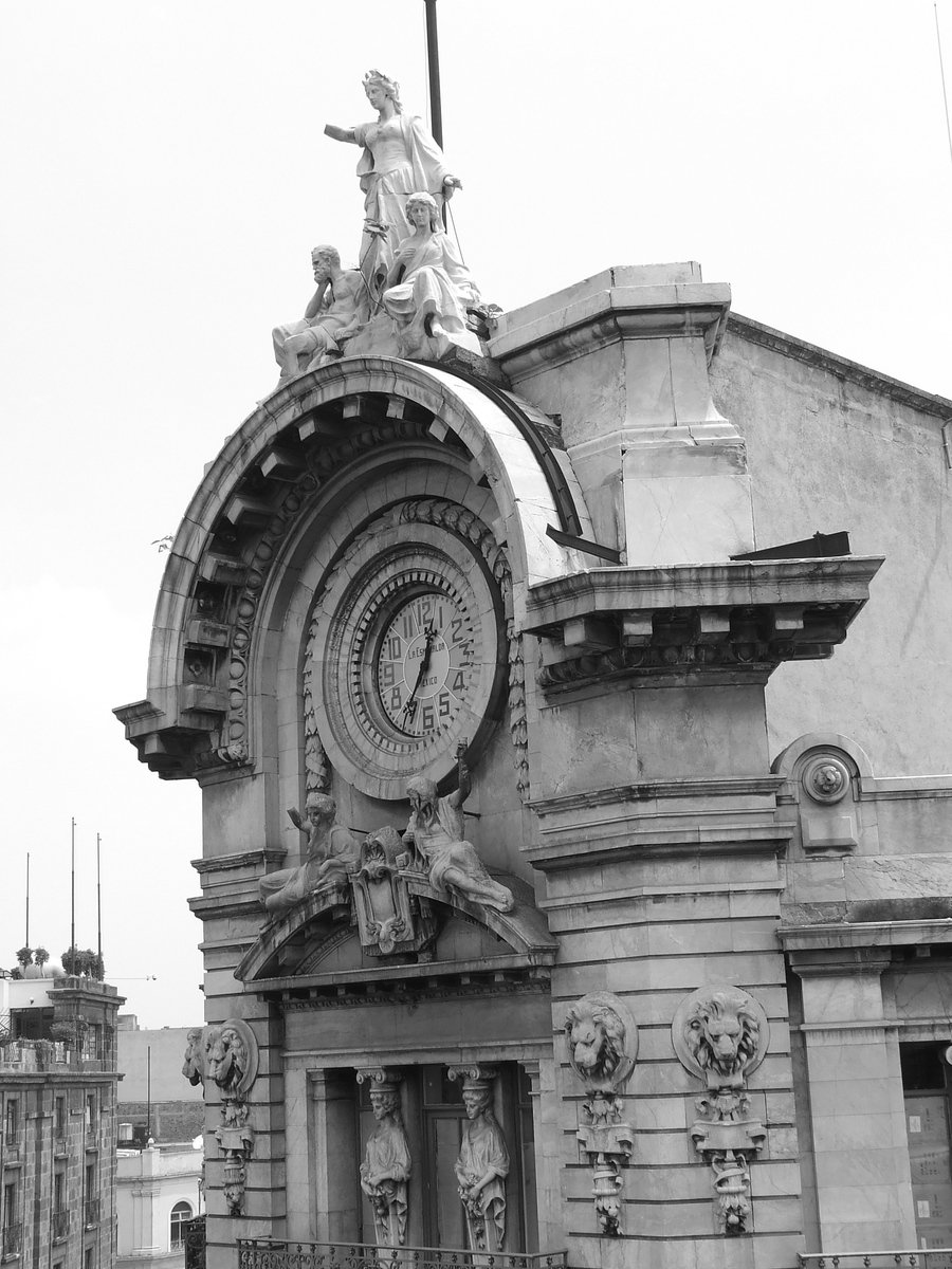 black and white pograph of large clock tower with statue on top