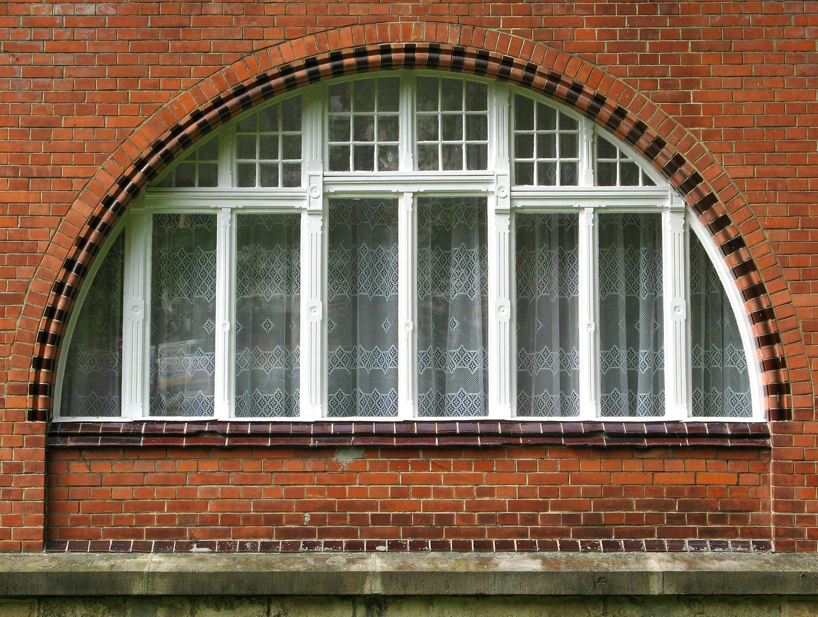 an arched window with black frame against a brick building