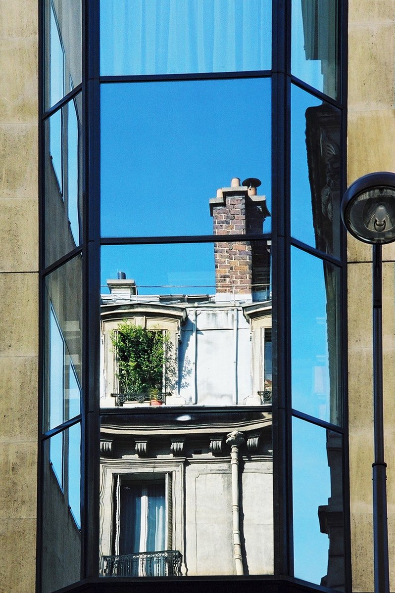 a reflection of an outside building in the side window of another building