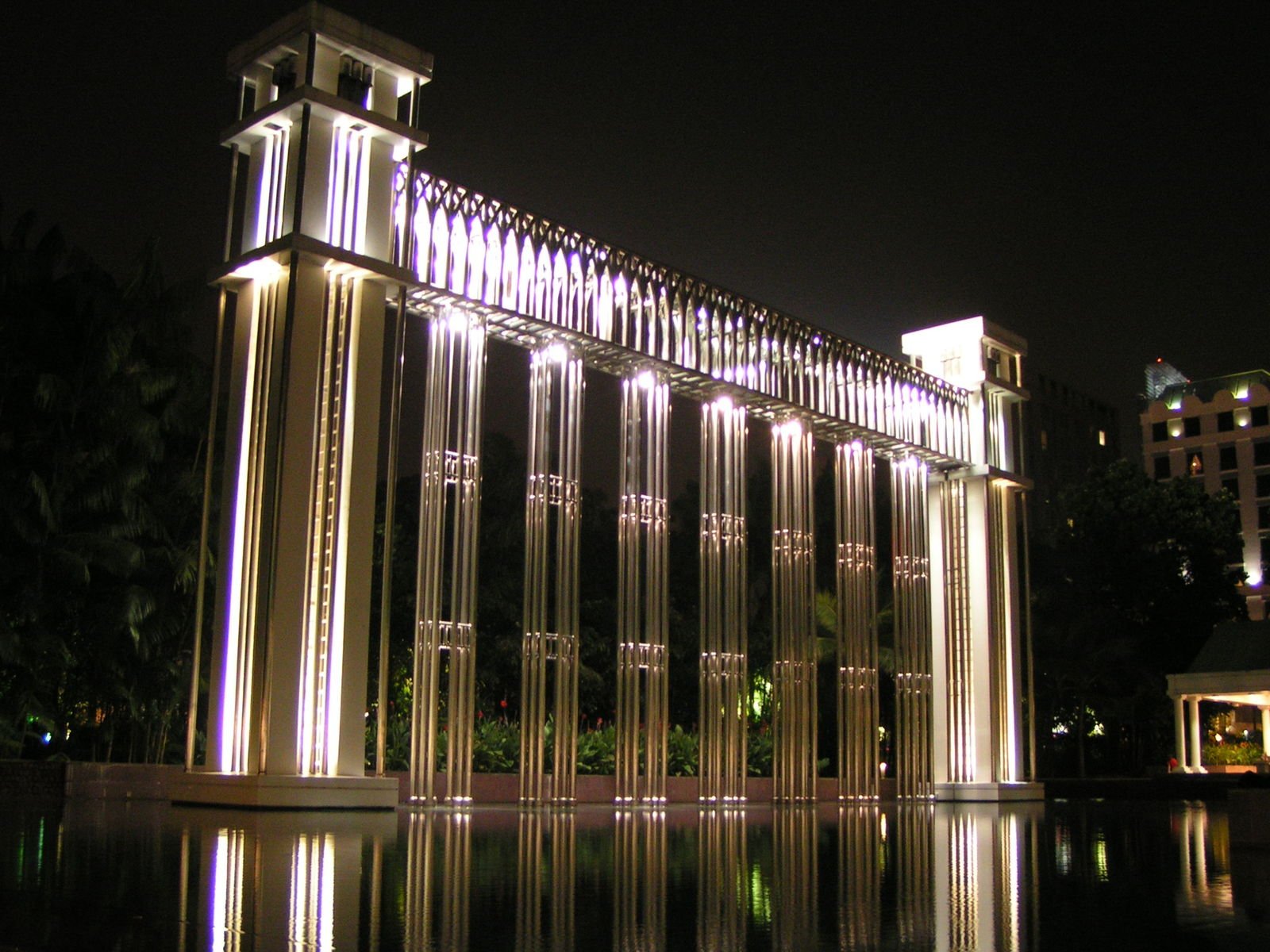 a large building made of metal poles is reflecting in the water