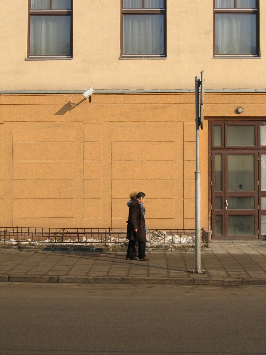 two men are walking down the sidewalk near a building