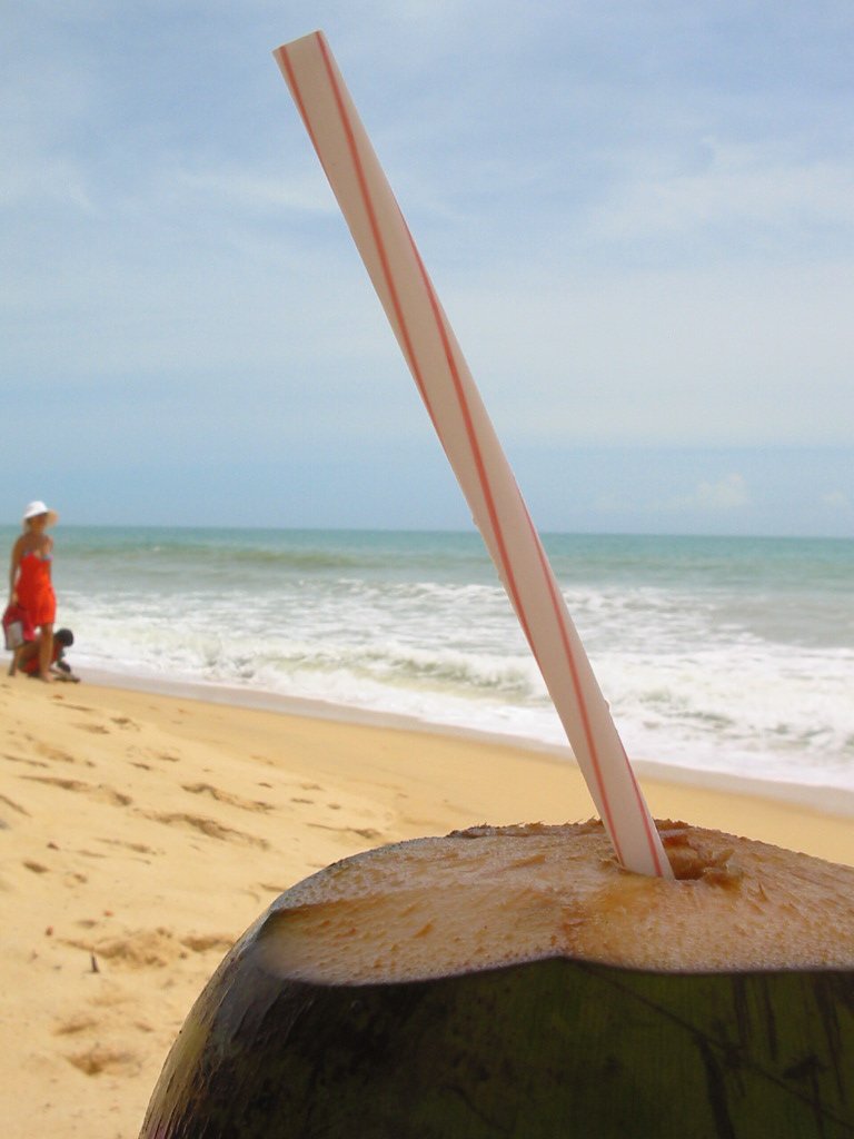 a drink sitting on top of a wooden barrel next to the ocean