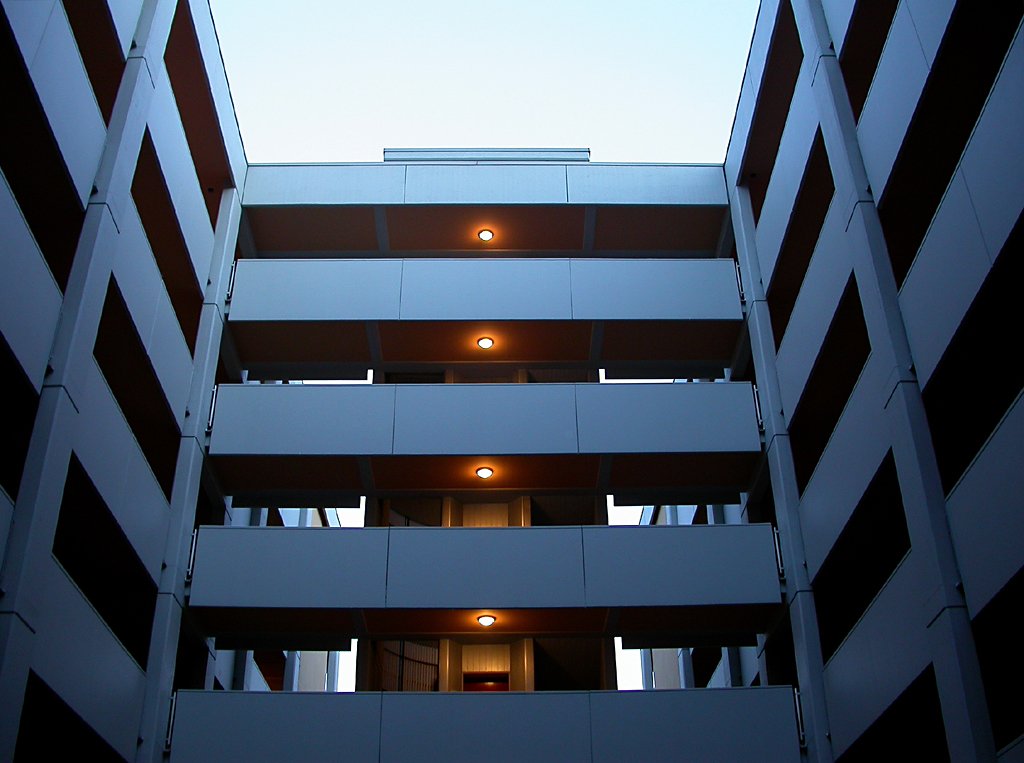 the top part of an apartment building with a door and balconies open at dusk