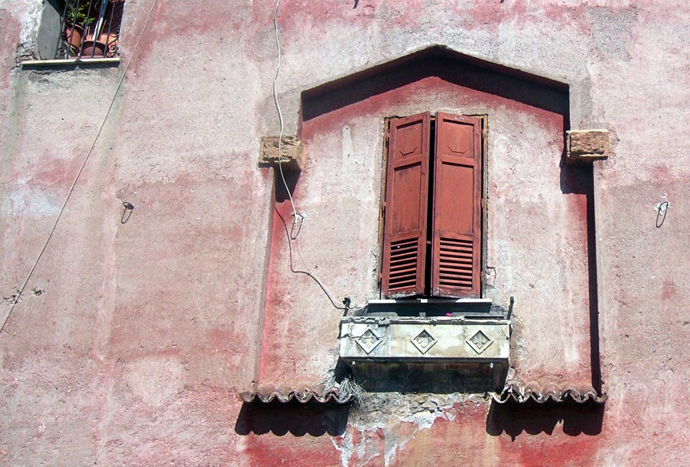 red building with wooden shutters and white bench