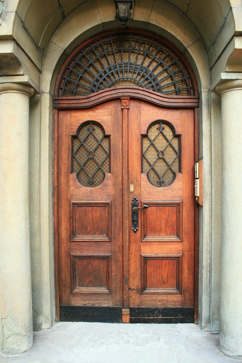two brown wooden doors sitting outside of a building