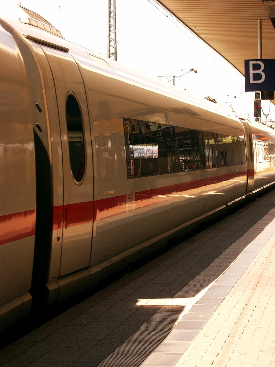a red and beige bullet train is pulled up to the station
