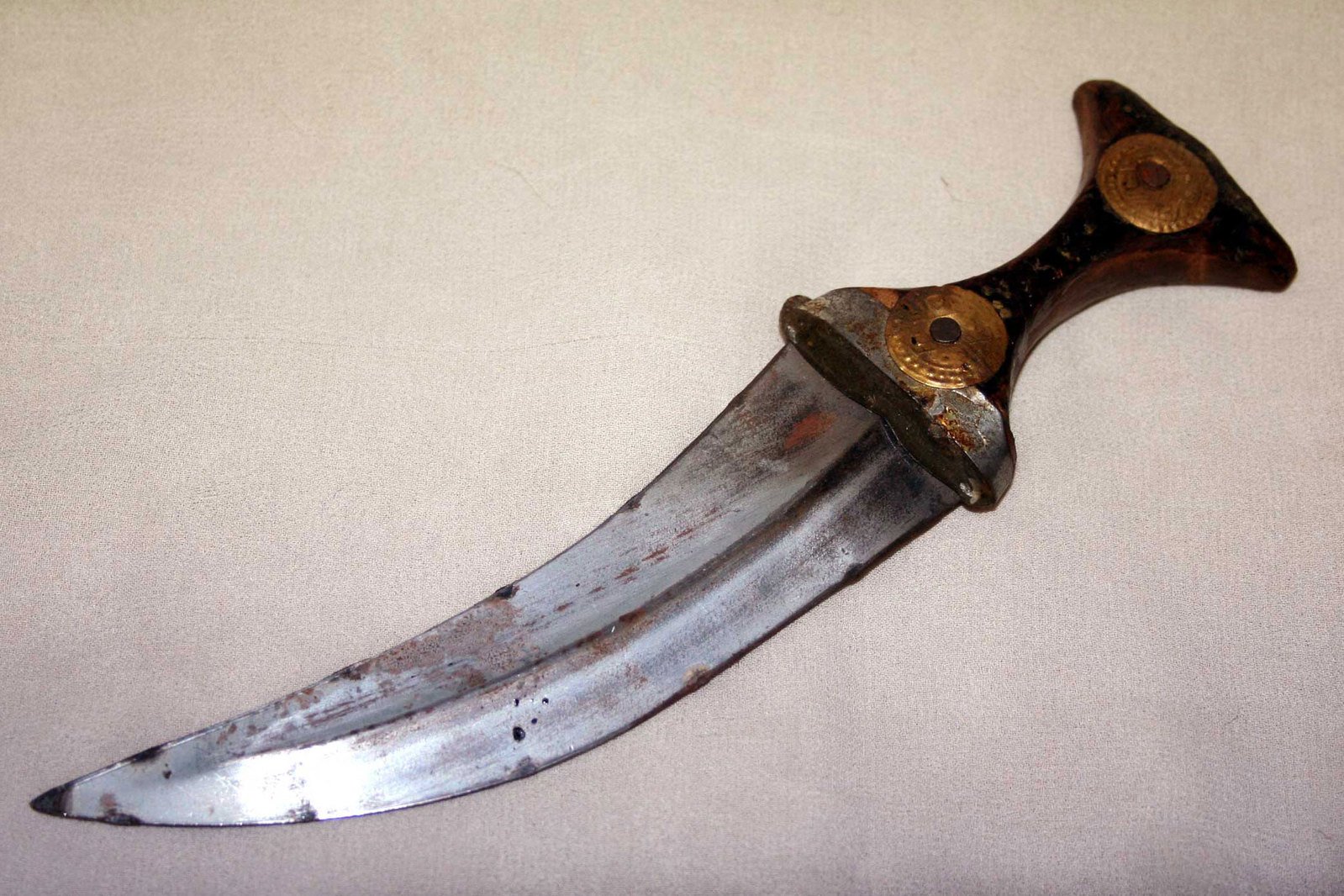 an old knife with a black handle lying on top of a white surface