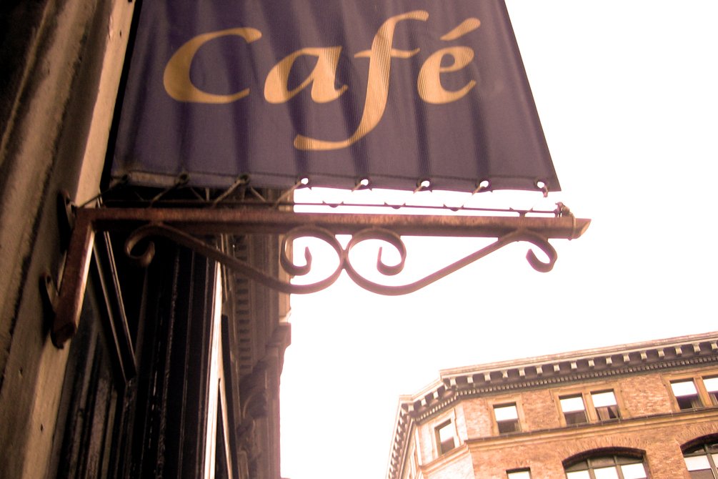 a large blue cafe sign above some buildings