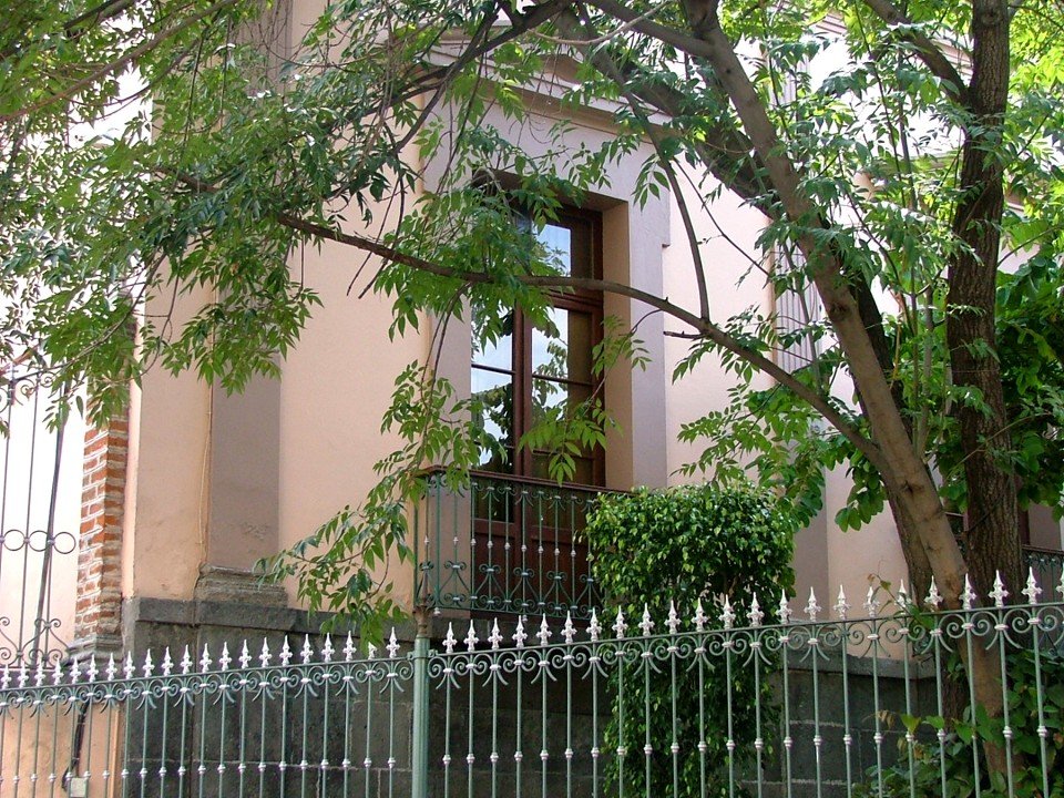 a building with a tall black gate and some trees