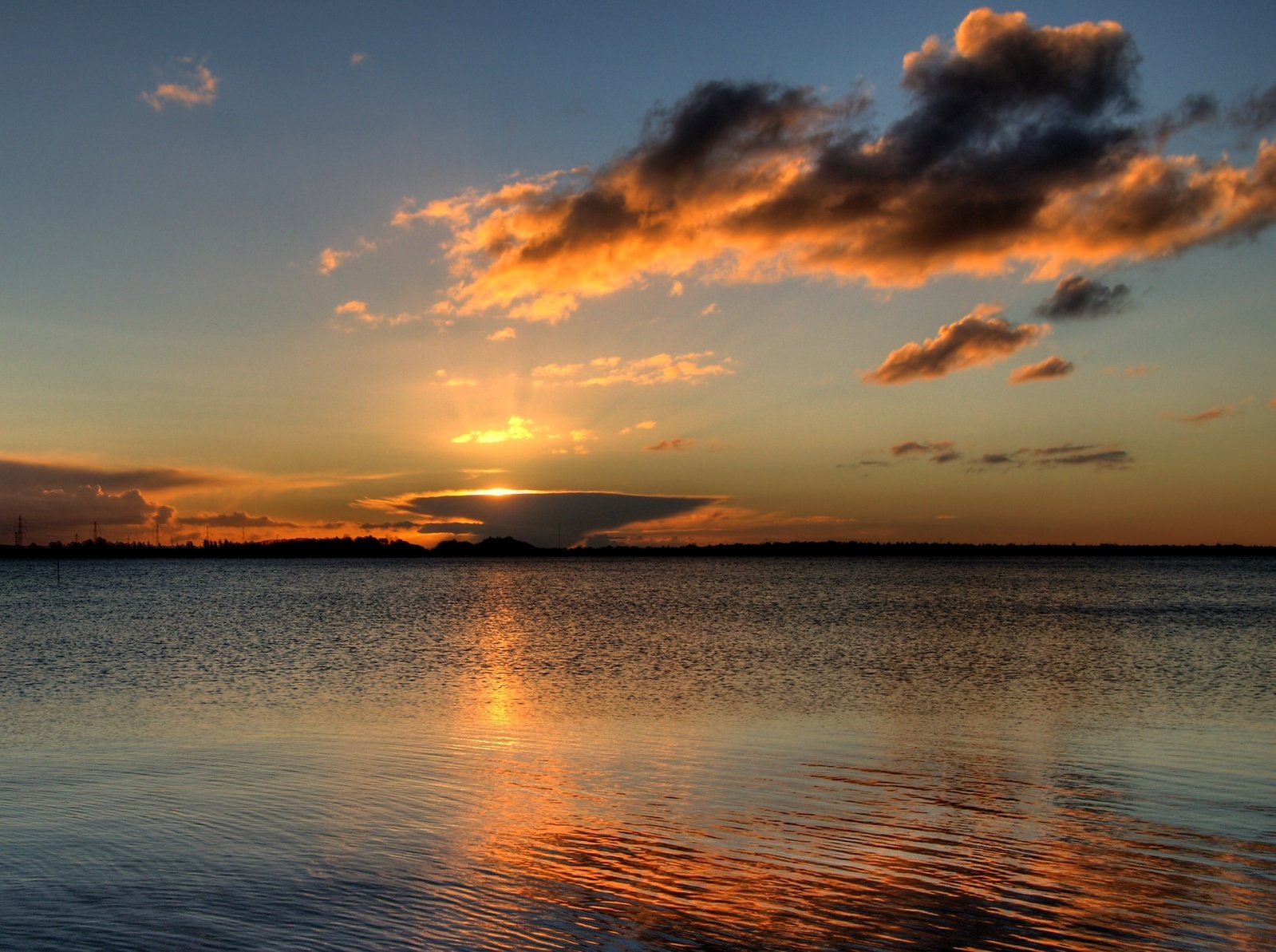 a sun setting over the ocean with clouds in the sky