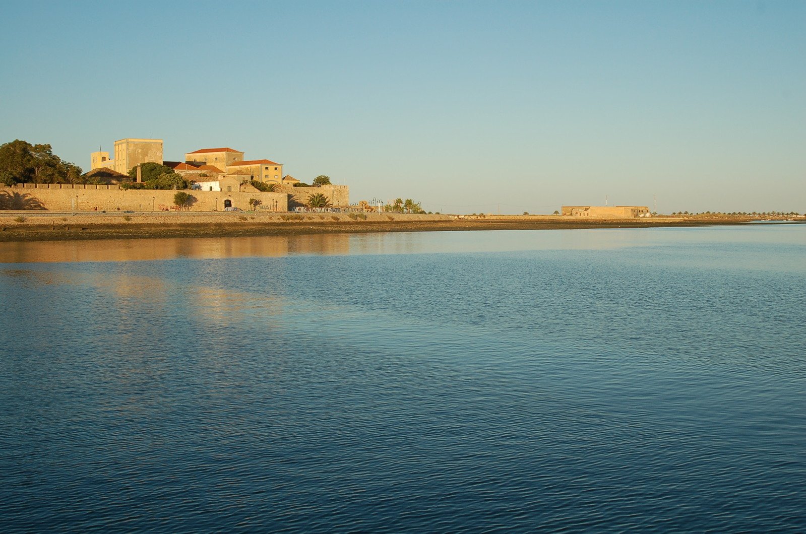 there is a small boat in the water by a castle