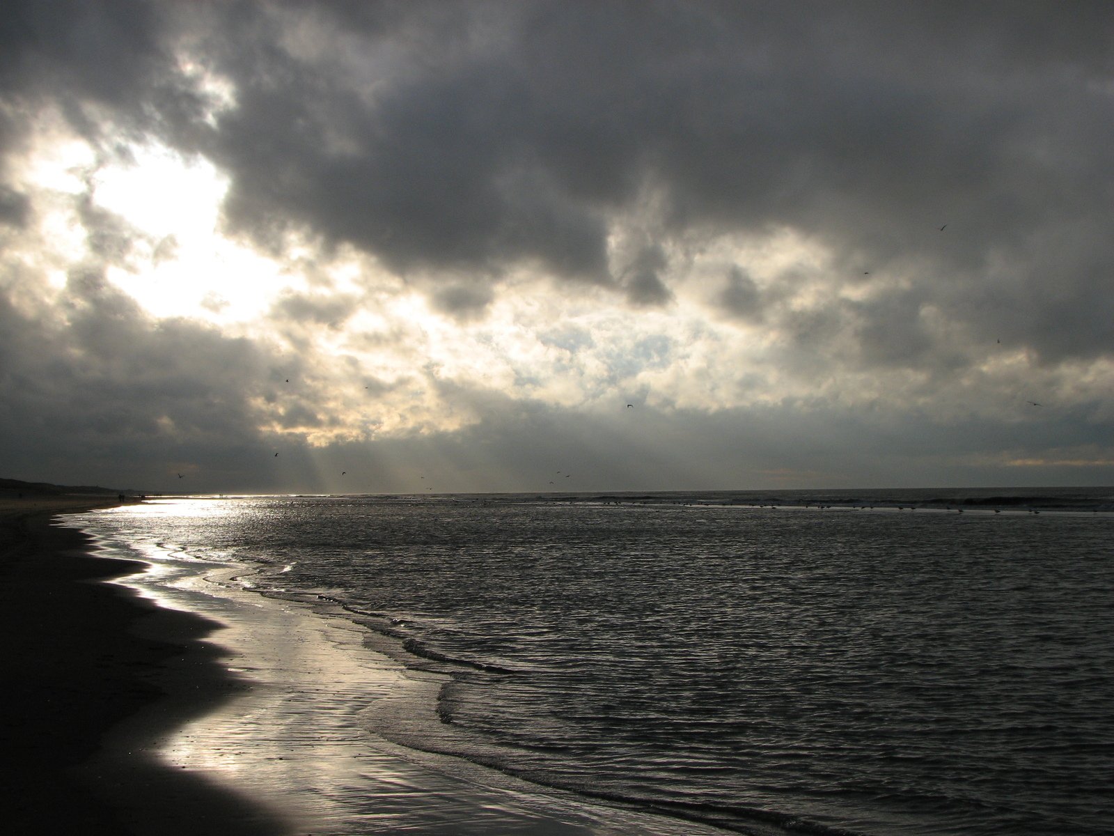 dark clouds are coming over the water at sunset