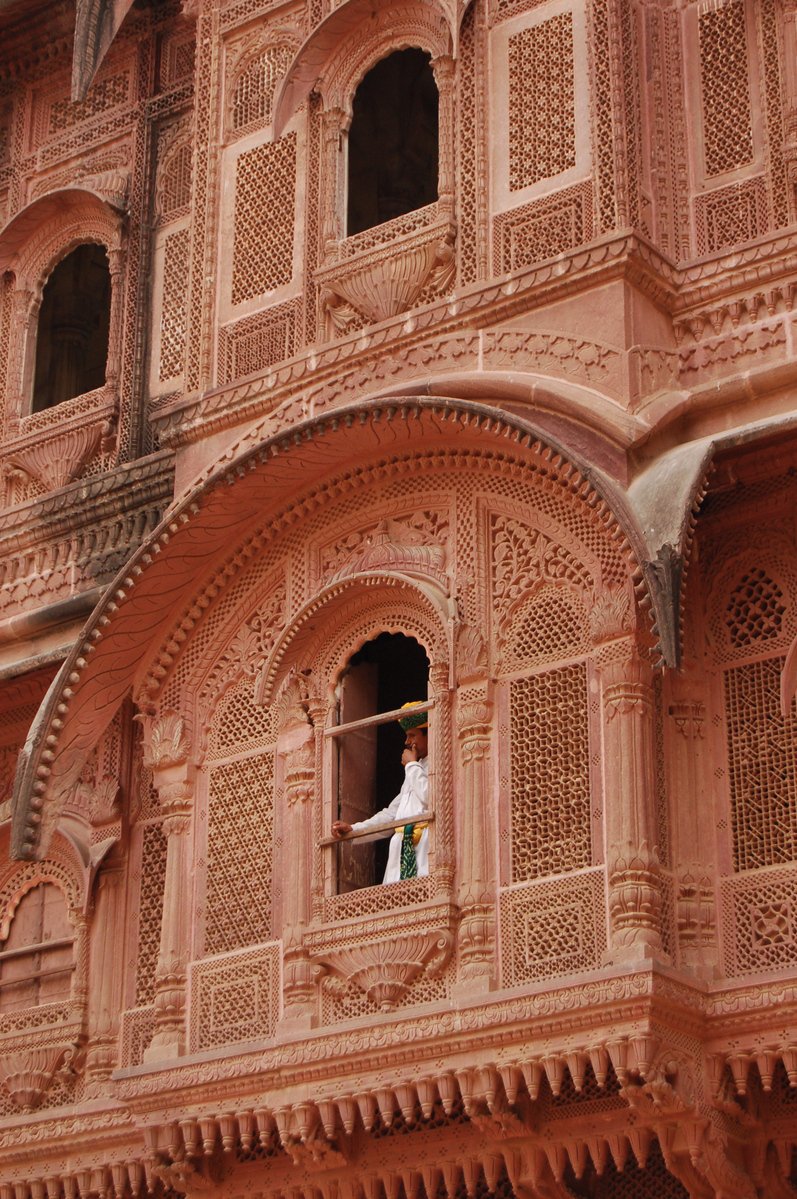 a person in an ornate red balcony with lots of windows