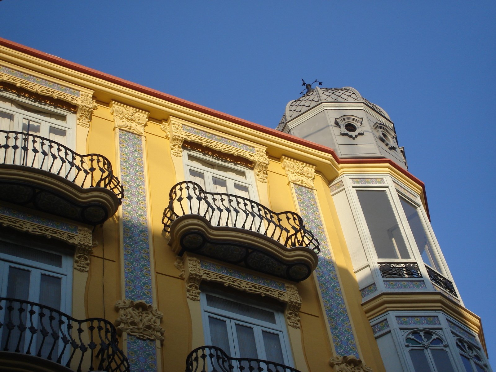 a tall yellow building with ornate balcony railings