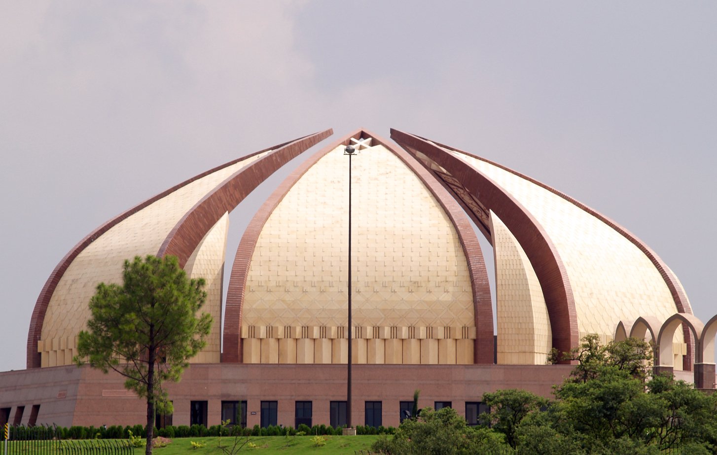 the dome of a building with a clock on top is surrounded by green trees