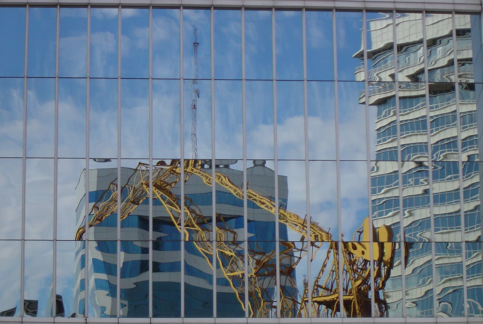 reflection of cranes in a skyscr building front