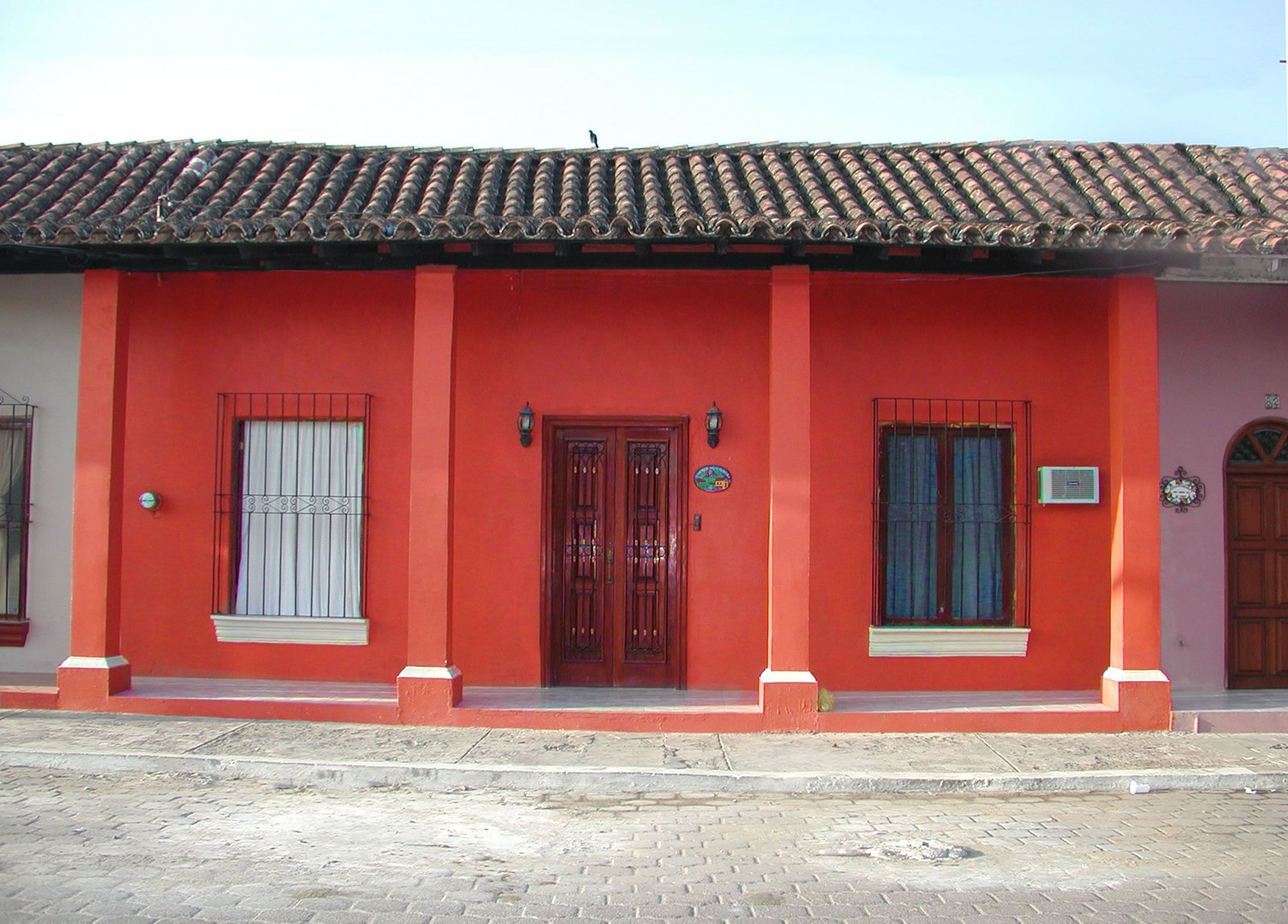 three windows in front of red stucco building with red and white trim